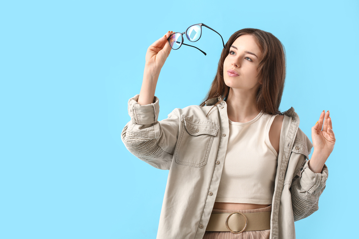 Young Woman Wearing Eyeglasses on Color Background